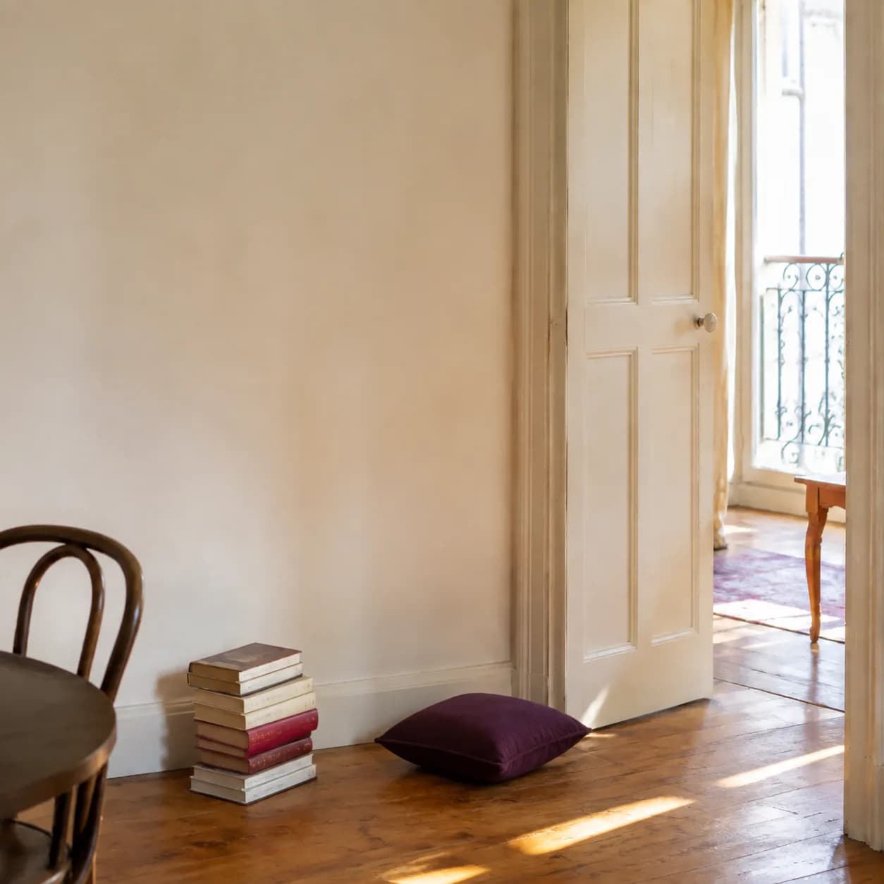 Des livres empilés au sol près d’un mur libre, en attendant une bibliothèque.